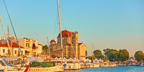 Yachts and waterfront with Ekklisia Isodia Theotokou Church at sunset in Aegina town